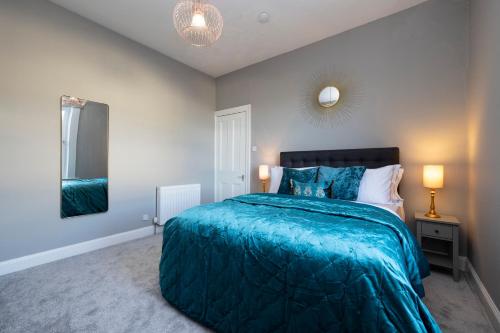 a bedroom with a blue bed and a mirror at Stylish George Street Apartment in Peebles