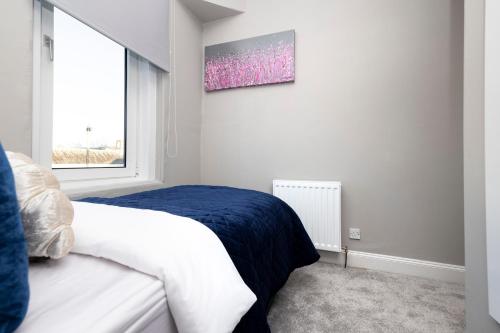 a white bedroom with a bed and a window at Stylish George Street Apartment in Peebles