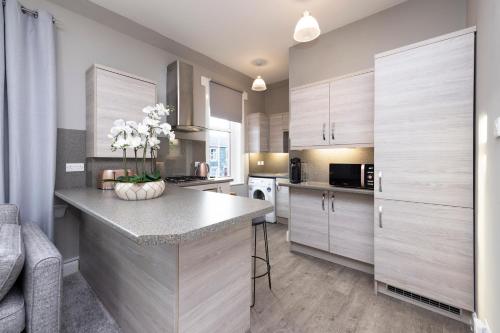 a kitchen with wooden cabinets and a counter with flowers on it at Stylish George Street Apartment in Peebles