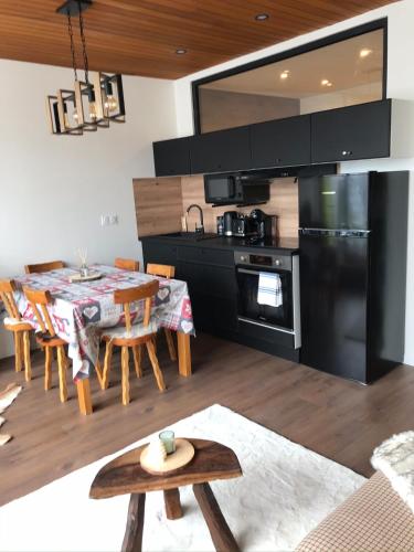 une cuisine et une salle à manger avec une table et une cuisine avec des appareils noirs dans l'établissement Superbe 2 pcs cabine terrasse vue féérique pistes et montagnes, à Auron