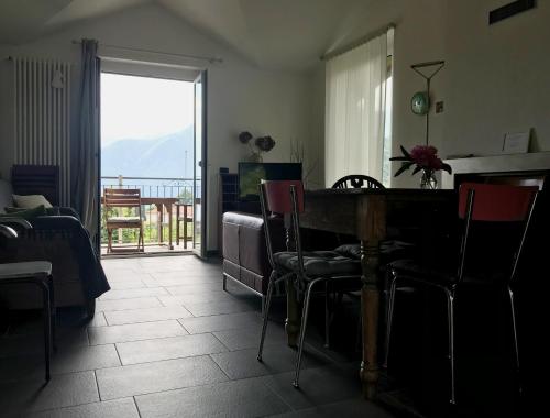 sala de estar con mesa y sillas y balcón en VILLA AS Campo Marzio en Lenno