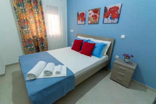 a blue bedroom with a bed with red and blue pillows at Nikopoleos 41 in Preveza
