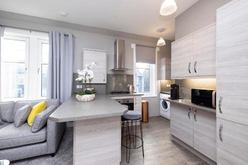 a kitchen and living room with a couch and a table at Stylish George Street Apartment in Peebles