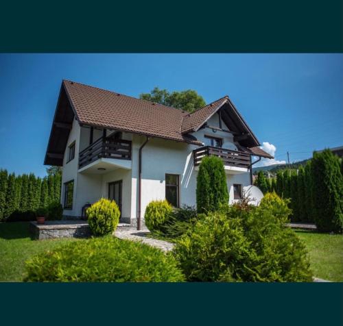une maison blanche avec un toit marron et quelques buissons dans l'établissement Jack Residence Busteni, à Buşteni