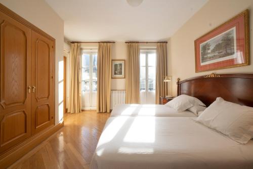 1 dormitorio con 1 cama grande y cabecero de madera en Miranda & Suizo, en San Lorenzo de El Escorial