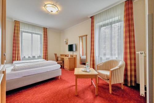 ein Hotelzimmer mit einem Bett und einem Stuhl in der Unterkunft Hotel Wittelsbach Oberammergau in Oberammergau