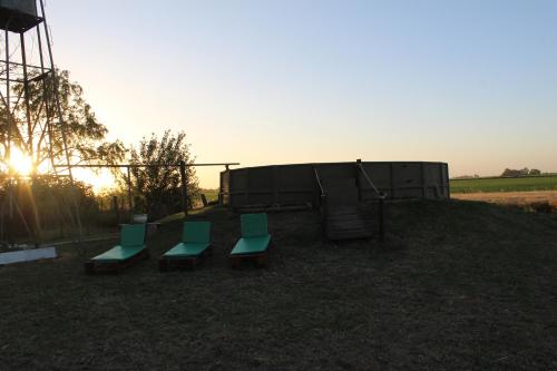 a playground with three green chairs and a slide at El Viejo Roble in Bragado
