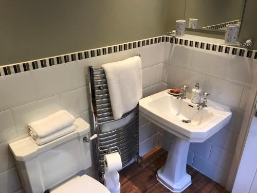 a white bathroom with a sink and a toilet at Heather Bank Cottage, Halifax. Yorkshire. HX2 7DD in Halifax