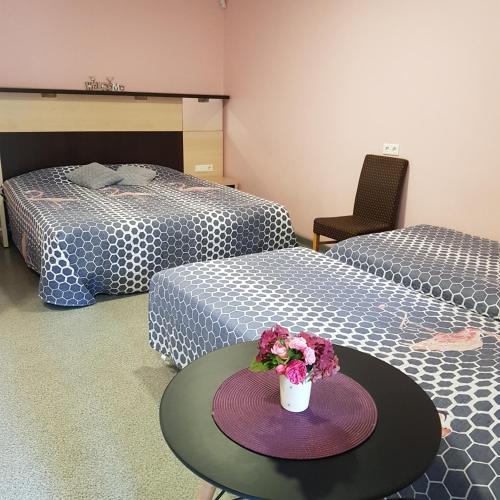 a room with two beds and a table with flowers on it at Cerību Liedags in Mērsrags