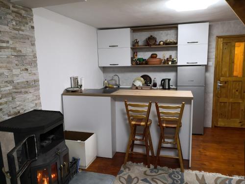a kitchen with a stove and two bar stools at Vikendica Ajla in Travnik
