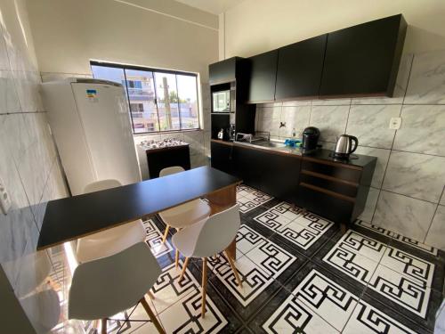 a kitchen with a counter and a refrigerator and chairs at Apartamento Centro in Ametista do Sul