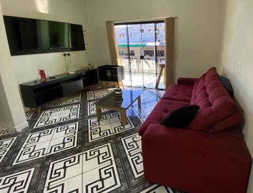 a living room with a red couch and a flat screen tv at Apartamento Centro in Ametista do Sul