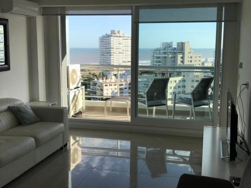 ein Wohnzimmer mit Couch und großem Fenster in der Unterkunft Torre One 2 Vista al Mar a metros de la playa in Punta del Este