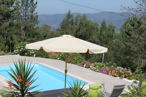 a white umbrella sitting next to a swimming pool at Casa Quelha da Presa in Espinho