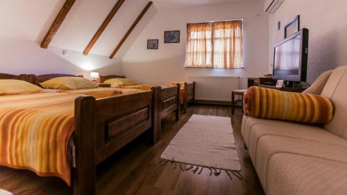 a bedroom with two beds and a couch at Guest House Rustico in Korenica