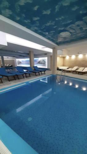 a large swimming pool with chairs and a blue ceiling at Ivkovic spa Milmari N16 in Kopaonik