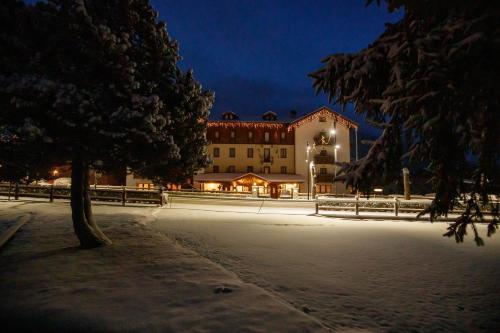 a large building in the snow at night at Hotel Villa Rina in Bormio