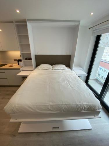 a large white bed in a room with a window at Modern Studio Apartment at The Hub in Gibraltar