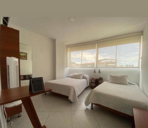 a bedroom with two beds and a desk and a window at Hotel Manhattan Barbosa in Barbosa