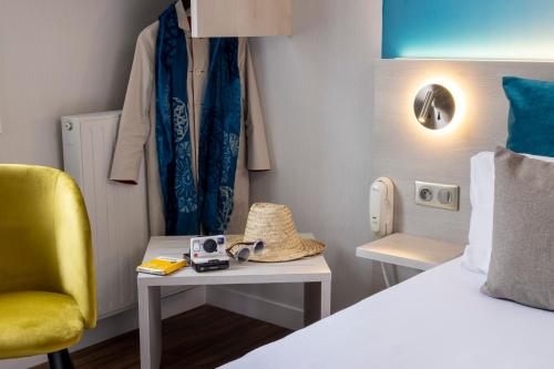 a small room with a bed and a yellow chair at Logis Hôtel-Restaurant LE FONTARABIE in Fontenay-le-Comte