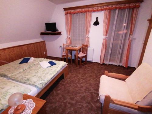 a bedroom with two beds and a table and a chair at Pension Krakonoš in Špindlerův Mlýn