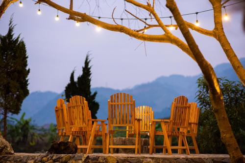 4 sillas de madera sentadas en una mesa bajo un árbol en Sapa Riverside Ecolodge & Spa, en Sa Pa