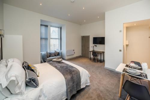 a hotel room with a large bed and a desk at Exquisite Serviced Studio @ Greenhead Central in Huddersfield