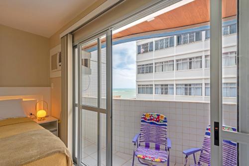 um quarto com uma cama e uma varanda com vista para o oceano em Studio com vista para o mar no centro de Guarapari com Wifi em Guarapari