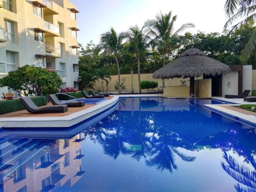 uma piscina com espreguiçadeiras e um edifício em Departamento en condominio Diamante Turquesa em Acapulco