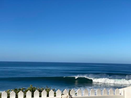 uma vista para o oceano a partir de uma praia com cadeiras brancas em CASA DO MAR em Jardim do Mar