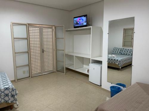 a living room with a couch and a tv on a wall at Pousada Xero in Capitólio