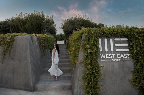 a woman standing on a ledge near a wall at West East Suites in Imerovigli