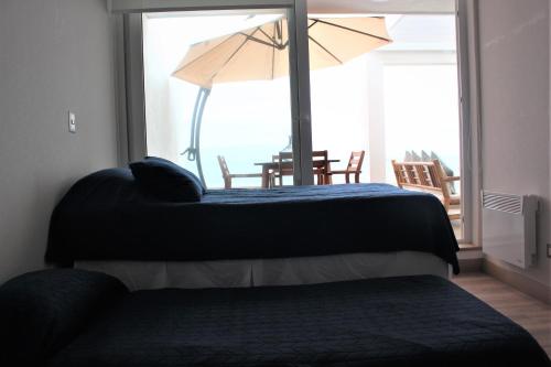 1 dormitorio con 2 camas y mesa con sombrilla en Descanso frente al mar, en Viña del Mar