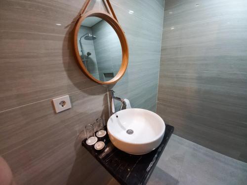 a bathroom with a sink and a mirror on a wall at ABISHA Hotel Sanur in Sanur