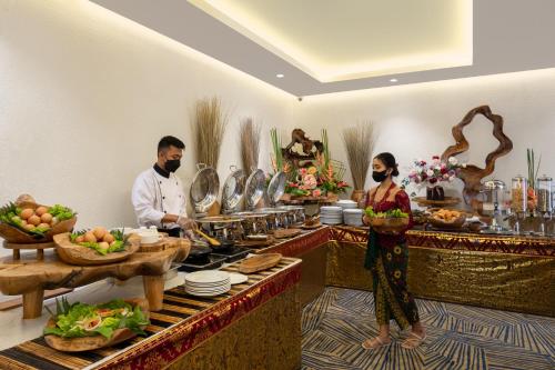 een man en een vrouw die eten bereiden in een buffet bij ABISHA Hotel Sanur in Sanur