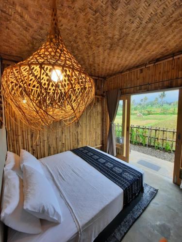a bedroom with a large bed with a chandelier at Sawah Ijen in Licin