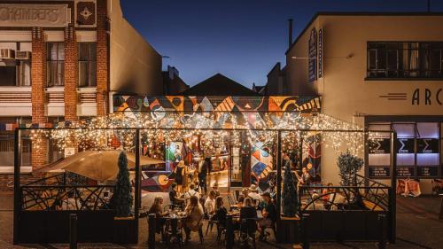 a group of people sitting at tables outside a building with lights at Archies Bunker Affordable Accommodation in Napier