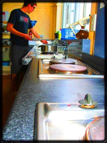 a man standing in a kitchen preparing food at Archies Bunker Affordable Accommodation in Napier