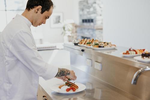 
a man in a chef's outfit preparing food in a kitchen at Azur Lodge in Queenstown
