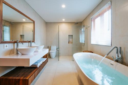 a bathroom with two sinks and a tub at Vienna Villas in Seminyak