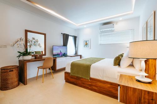 a bedroom with a bed and a desk and a television at Vienna Villas in Seminyak