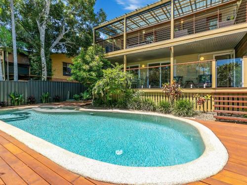 a swimming pool in front of a house at Noosa Beachhouse in Noosa Heads
