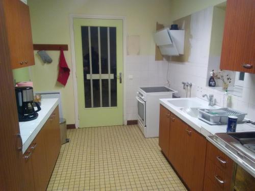 a kitchen with a white sink and a green door at Mlle Labeaume in Aigueperse