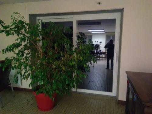 a man standing in an office through a door with a plant at Mlle Labeaume in Aigueperse