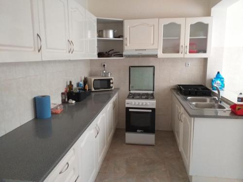 uma cozinha com armários brancos e um forno com placa de fogão em Bright apartment in the town center em Praia