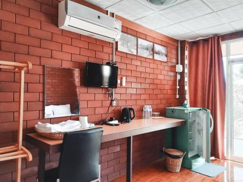 a kitchen with a table and a tv on a brick wall at Pruksatara Garden in Phu Ruea