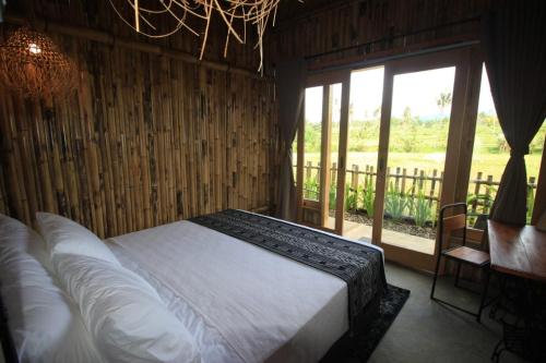 a bedroom with a bed and a large window at Sawah Ijen in Licin