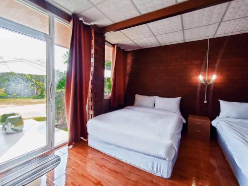two beds in a room with a large window at Pruksatara Garden in Phu Rua