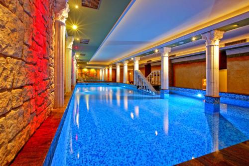 a swimming pool in a hotel with a stone wall at Pałac Saturna in Czeladź