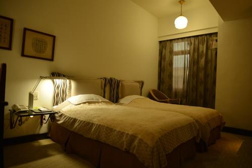 a bedroom with a bed and a lamp and a window at Kingship Hotel Kaohsiung Inter Continental in Kaohsiung